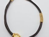 un gros plan d'un bracelet noir et doré posé sur une surface blanche