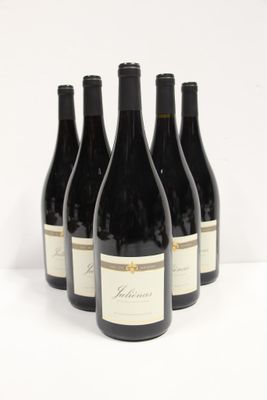 six bottles of red wine are lined up on a white surface