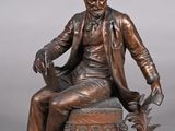 bronze statue of a man sitting on a chair with a dog