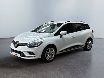 Une voiture blanche est garée dans une pièce blanche au sol noir.