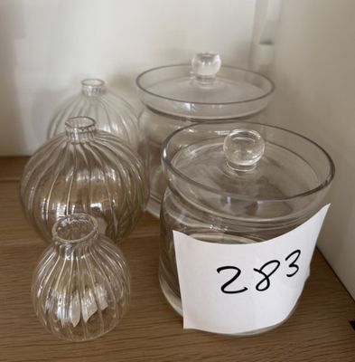 trois récipients en verre transparent posés sur une table, accompagnés d'une étiquette de prix