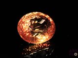 an orange diamond on a reflective surface with a black background