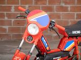 a small red motorcycle parked in front of a brick wall
