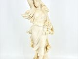 une statue ancienne représentant une femme tenant un oiseau dans la main