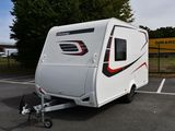 un petit camping-car blanc garé sur un parking