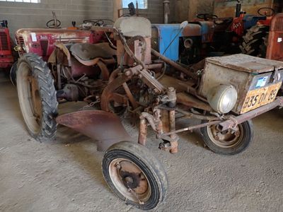 un vieux tracteur dans un garage, à côté d'autres vieux tracteurs