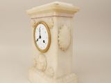 a white clock sitting on top of a white pedestal
