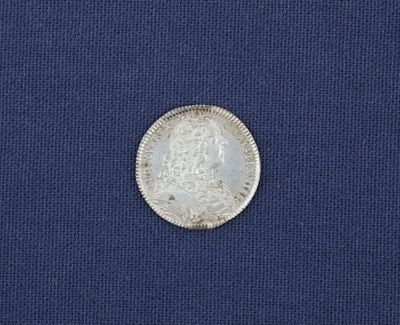une vieille pièce d'argent posée sur un tissu bleu