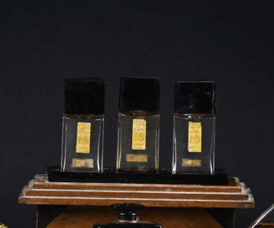 three bottles of perfume on a wooden shelf with a pen and paper
