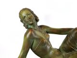 a bronze statue of a woman laying down on the ground