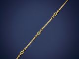 a gold bracelet with a green stone on a blue background
