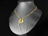 un collier en or posé sur un socle de mannequin, sur fond noir