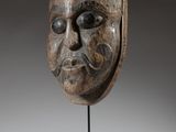 a wooden mask on a stand with a gray background