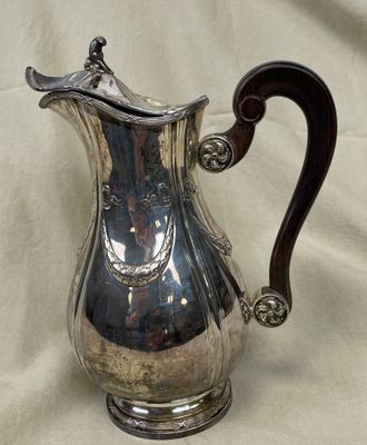 une cafetière en argent avec une anse, posée sur une table
