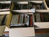 de nombreux livres rangés dans des cartons posés par terre