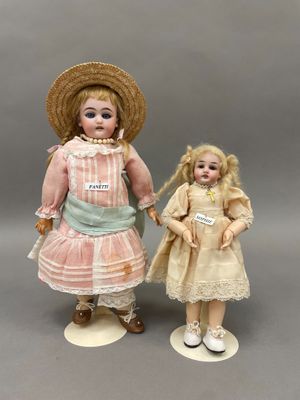 une paire de poupées en porcelaine représentant une fille et un garçon, vêtus de robes et coiffés de chapeaux