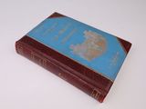 un vieux livre à la couverture bleue posé sur une surface blanche