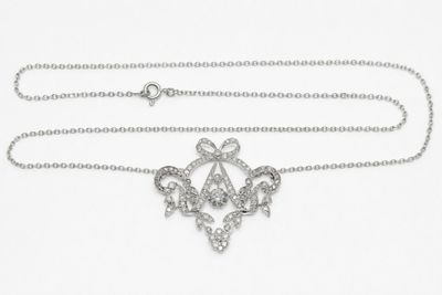 a close up of a necklace with a diamond pendant on a chain