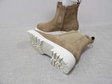 beige sued ankle boots with white soles on a white surface