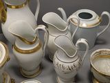 a lot of white and gold dishes and cups on the table