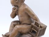 statue of a baby sitting on a bench with a basket in his lap