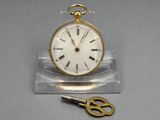 a small gold pocket watch with a pair of scissors next to it