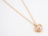 a close up of a gold necklace with a heart shaped pendant on it