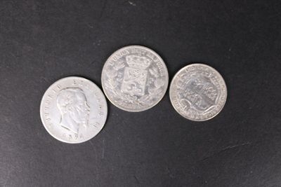 trois pièces d'argent posées les unes à côté des autres sur une surface noire