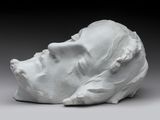 une sculpture blanche représentant la tête d'un homme posée sur une table