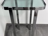 une table en verre avec un piètement en métal posée sur un sol carrelé