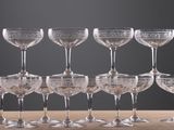 twelve wine glasses are lined up on a wooden table