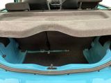 the back of a blue car with its trunk open and seats folded down