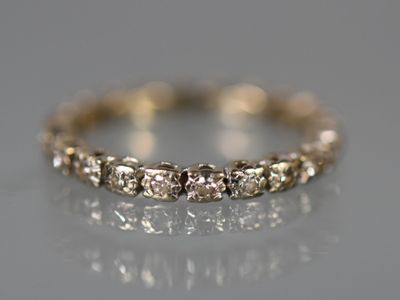 un gros plan d'une bague en diamant posée sur une surface réfléchissante