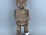 statue d'un homme tenant un morceau de bois et portant une étiquette sur la poitrine
