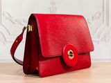 a red purse sitting on top of a wooden table