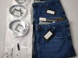 Deux paires de jeans bleus et une chemise blanche sont posées sur une table.