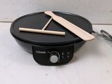 an electric skillet with two wooden sticks sitting on top of it