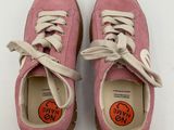 pair of pink shoes with orange stickers on them sitting on a white surface