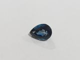 a blue topazte pear shaped stone on a white surface