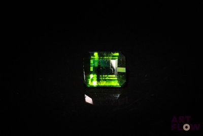 un gros plan d'une bague en verre vert posée sur une surface noire