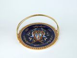 a blue plate with a gold handle on a white surface