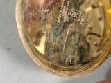 a person holding a gold pocket watch in their hand