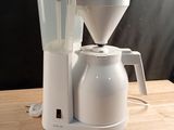 a white coffee maker sitting on a wooden table