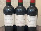 three bottles of red wine sitting on top of a wooden table