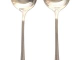 two silver spoons sitting next to each other on a white surface