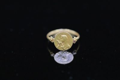 a close up of a gold ring with a coin on it