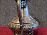 a silver pitcher on a red cloth on a table