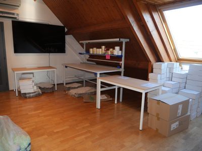 a room with a lot of boxes on the floor and a flat screen tv on the wall