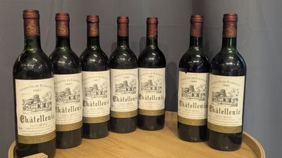 six bottles of wine are lined up on a wooden barrel
