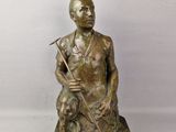 statue en bronze représentant un homme avec un chien, posée sur un socle